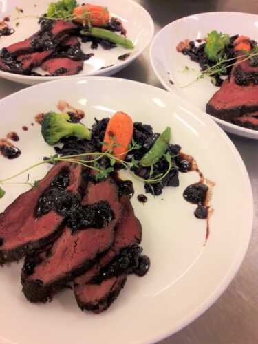 Reindeer meat placed on a plate with herbs and vegetables