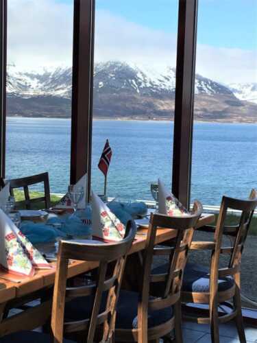 Oppdekket bord forran et vindu med utsikt over fjord og fjell