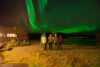 Five persones are standing outside watching the Northern Light sky in the month October