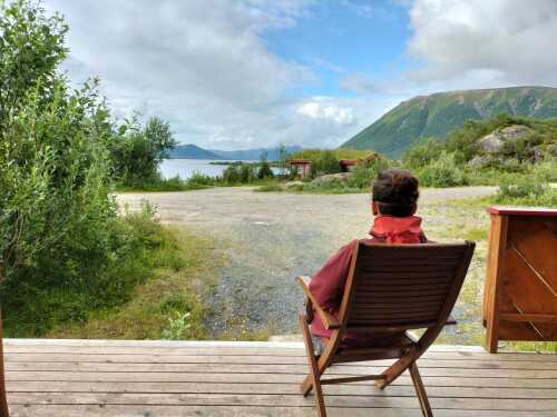 En person sitter på terrassen og nyter fjord- og fjellutsikten