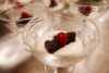 Plumpudding med rød coctailbær i hvit dessert saus i blankt dessertglass