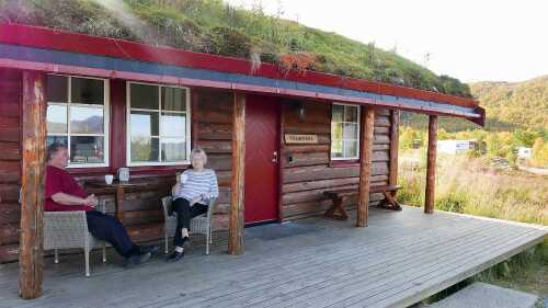To personer nyter kaffe på terrassen utenfor studiohytta