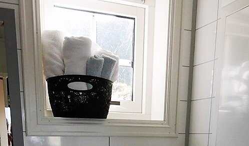 Sort kurv med hvite og blå håndklær i vinduskarmen